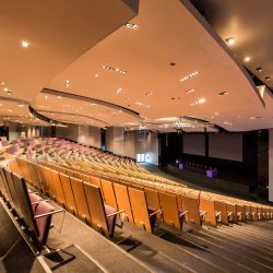 Spacious modern lecture hall theater with lighting on dropped ceiling and seats